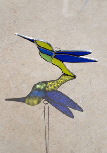 Colorful handmade stained glass hummingbird window suncatcher catching sunlight, home decoration