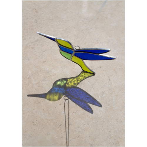 Colorful handmade stained glass hummingbird window suncatcher catching sunlight, home decoration