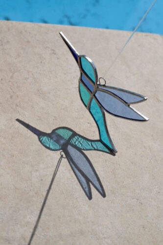 Colorful handmade stained glass hummingbird window suncatcher catching sunlight, home decoration