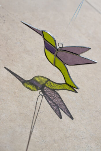 Colorful handmade stained glass hummingbird window suncatcher catching sunlight, home decoration