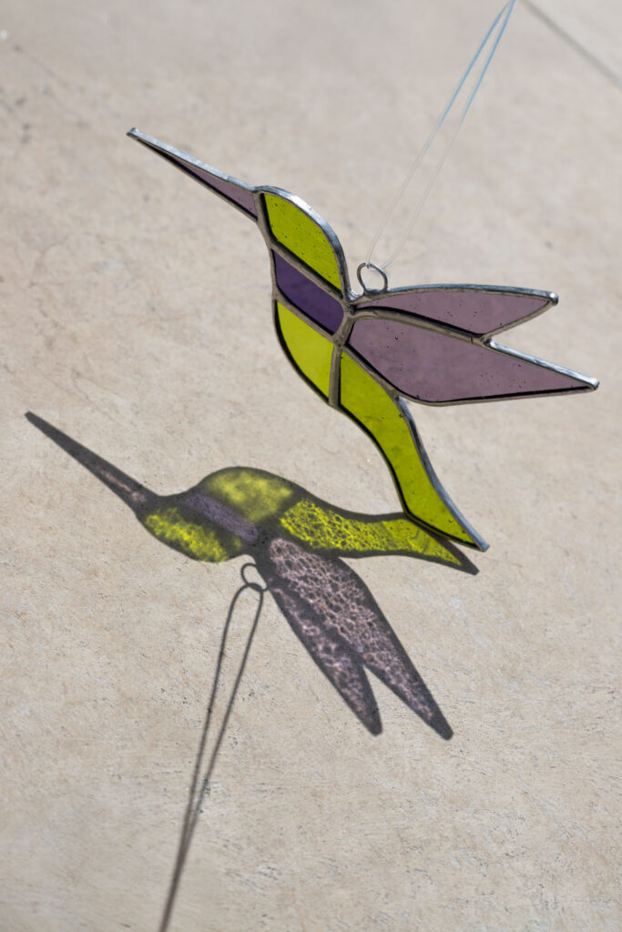 Colorful handmade stained glass hummingbird window suncatcher catching sunlight, home decoration