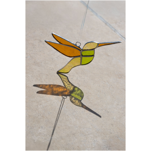 Colorful handmade stained glass hummingbird window suncatcher catching sunlight, home decoration