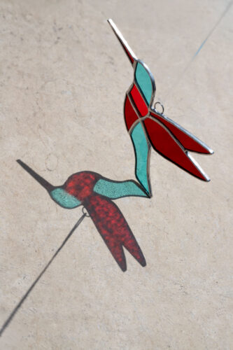 Colorful handmade stained glass hummingbird window suncatcher catching sunlight, home decoration