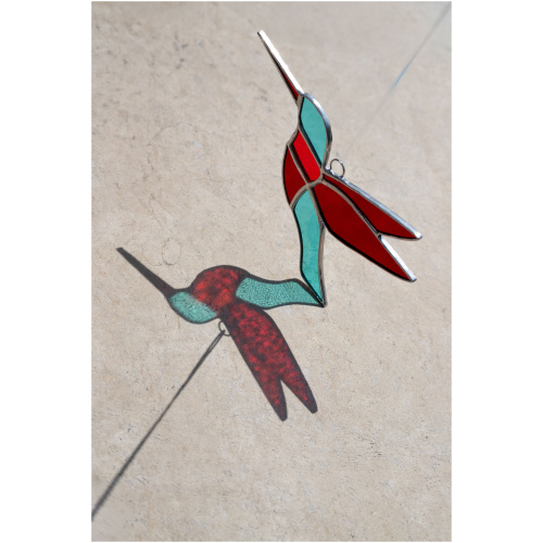 Colorful handmade stained glass hummingbird window suncatcher catching sunlight, home decoration