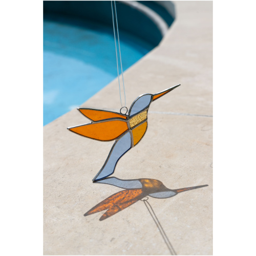 Colorful handmade stained glass hummingbird window suncatcher catching sunlight, home decoration