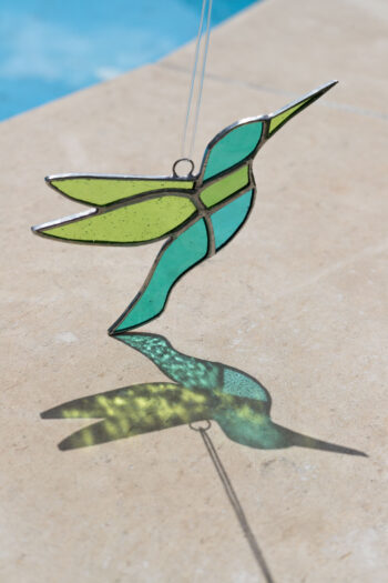 Colorful handmade stained glass hummingbird window suncatcher catching sunlight, home decoration