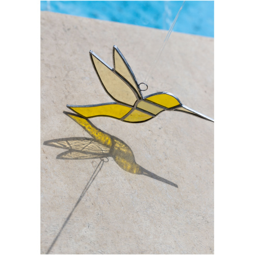 Colorful handmade stained glass hummingbird window suncatcher catching sunlight, home decoration