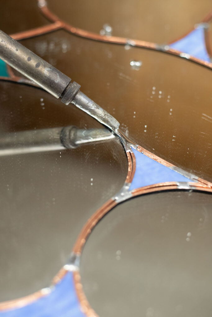 Handcrafted stained glass wall mirror with organic hand-drawn lines and blue textured glass
