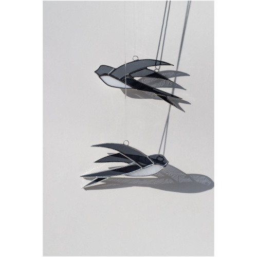 Handcrafted stained glass swallow sun catcher casting a graceful bird-shaped shadow